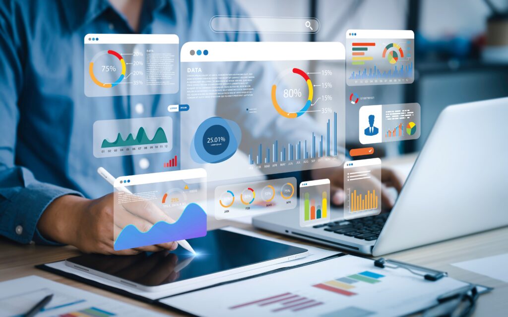 Ein Geschäftsmann arbeitet an einem Tablet und einem Laptop, umgeben von schwebenden digitalen Diagrammen und Grafiken. Diese Visualisierungen repräsentieren die umfangreichen Analyse- und Berichterstattungsfunktionen von Sage 100, die Unternehmen dabei helfen, ihre Finanzdaten effizient zu verwalten und fundierte Entscheidungen zu treffen